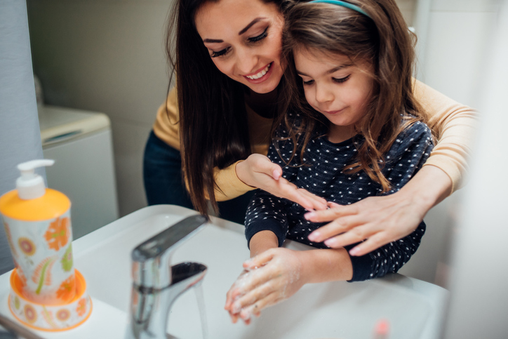 Happy woman washing hands with her daughter